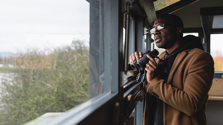 A man uses binoculars in a hide